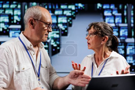 Photo for Octogenarian employees working to maintain uptime in high tech workspace. Efficient workers brainstorming solutions to data center blade servers crashing, trying to fix components - Royalty Free Image