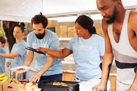 Junge Freiwillige kochen und verteilen Lebensmittel an Bedürftige. Behinderte und multiethnische Menschen kommen zusammen, um Unterkünfte und humanitäre Hilfe zur Förderung der Einheit und des Mitgefühls in der Gemeinschaft bereitzustellen.