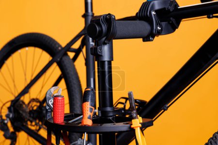 Foto de Foto mostrando herramientas de trabajo especializadas dispuestas en el soporte de reparación, listo para la fijación de la bicicleta dañada. Primer plano de equipos profesionales, llave y destornillador para la reparación de bicicletas. - Imagen libre de derechos