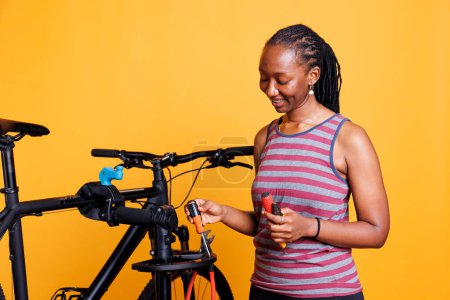 Gesunde schwarze Frau bereitet professionelle Werkzeuge für Reparatur und Wartung von Fahrrädern vor. Afroamerikanerinnen reparieren ein Fahrrad, inspizieren, justieren und sichern dessen Komponenten mit fachmännischer Präzision.