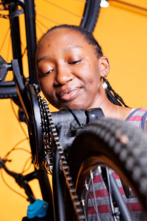 Photo for Detailed view of black woman carefully examining bicycle chain stay for optimal cycling. Young lady in up-close shot, showcases her attention to detail as she diligently maintains her bike components. - Royalty Free Image