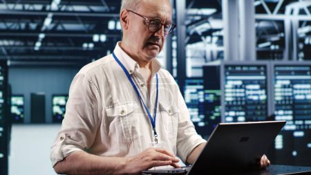 Trained engineer expertly managing data while navigating in industrial server room. Specialist ensuring errorless cybersecurity protection, optimizing systems and performing necessary updates