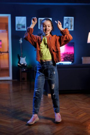 Photo for Popular child takes part in viral dance trend after seeing favorite celebrities doing it, filming family channel video in apartment for children audience. Smiling kid does trendy dancing challenge - Royalty Free Image