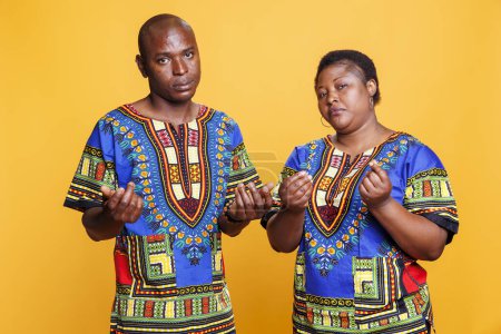 Téléchargez les photos : Homme et femme afro-américain confiant montrant geste d'argent comptant avec des doigts portrait. Couple noir avec expression faciale sérieuse demandant un paiement et regardant la caméra - en image libre de droit