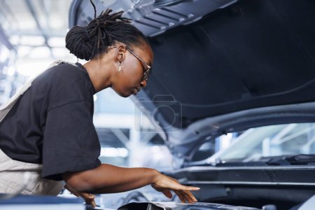 BIPOC Frau im Autoservice mit professionellem mechanischem Werkzeug, um defektes Zündsystem zu reparieren. Qualifizierter Spezialist für die Befestigung von Kundenfahrzeugen in Werkstätten, um eine optimale Leistung der Fahrzeuge zu gewährleisten