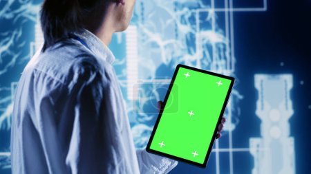Skillful IT consultant using green screen tablet to implement artificial intelligence parallel processing. Dilligent supervisor oversees chroma key device enabling AI to do machine learning inference