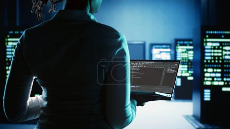 Photo for Meticulous expert working in server hub, running code on laptop, monitoring technologically advanced electronics clusters of blade servers, networking systems and storage arrays - Royalty Free Image