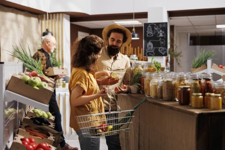 Man and woman buying products in zero waste store designed to minimize plastic usage, creating positive environmental impact. Customers looking for nutritious ethically sourced groceries