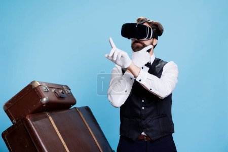 Doorman employee uses vr glasses on camera and posing next to pile of suitcases, having fun with modern 3d interactive vision headset. Bellboy exuding professionalism and modernization.