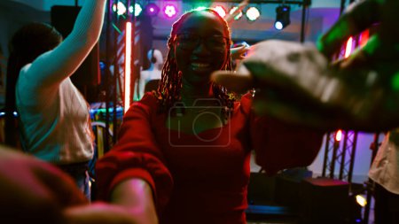 Téléchargez les photos : Point de vue de fille dansant avec quelqu'un au club, profitant d'une fête disco sur la piste de danse discothèque. Groupe d'amis s'amuser à la boîte de nuit en écoutant de la musique électronique, divertissement. Coup de main. - en image libre de droit