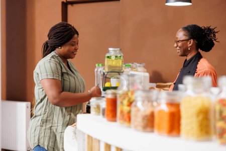 Tiendas sonrientes de mujeres negras en el mercado de alimentos biológicos, comprando productos orgánicos frescos y apoyando prácticas sostenibles y cero residuos. Cliente mujer que se prepara para pagar por sus productos sostenibles.