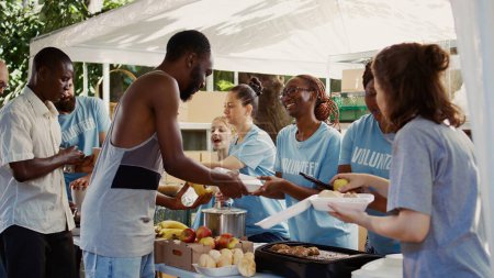 Los voluntarios multiétnicos distribuyen alimentos donados, extendiendo una mano de ayuda a las personas sin hogar y hambrientas. Jóvenes voluntarios comparten comidas frescas y complementarias con los menos afortunados.