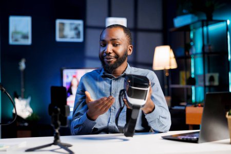 Creador de contenido técnico filmando revisión tecnológica de gafas VR futuristas recién lanzadas, probándolas y dando sus impresiones al público. Estrella de Internet sondeando dispositivo de realidad virtual