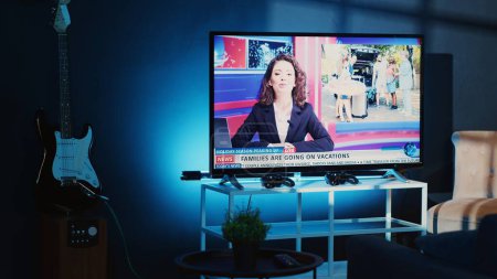 Photo for Close up shot of TV left open at night in cozy dimly lit apartment showing news channel. Home entertainment system showing broadcast of television reports in living room illuminated by blue light - Royalty Free Image