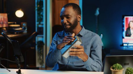 Foto de Africano americano estrella de Internet haciendo revisión de tecnología de altavoz portátil Bluetooth para el canal de plataformas en línea. Influenciador de BIPOC presentando dispositivo de reproducción de música a su audiencia - Imagen libre de derechos