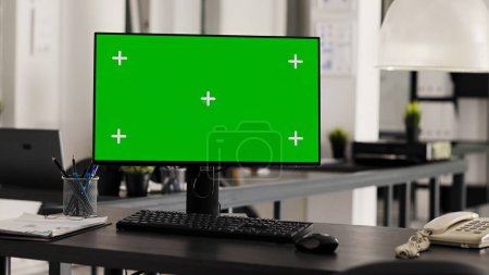 Photo for Empty office desk with pc running greenscreen on display, showing isolated chromakey template in coworking space. Workstation in open floor plan with monitor and copyspace layout. - Royalty Free Image