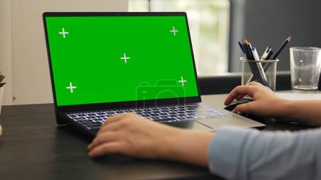 Photo for Woman analyst works on laptop with greenscreen isolated display, checking pc with blank mockup template. Young person working on business tasks using chromakey copyspace screen. - Royalty Free Image