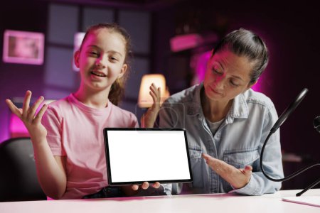 Photo for Girl and mother film reaction video for gen Z subscribers, looking on mockup tablet at online videos. Child media star and her parent watching funny internet clips on isolated screen device - Royalty Free Image