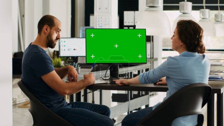 Photo for Startup team looking at pc with greenscreen, small business office desk. Company workers analyzing isolated copyspace template, doing teamwork for income development, chromakey on display. - Royalty Free Image