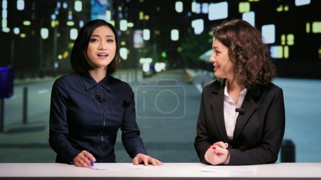 Newscasters team hosting night show in newsroom, talking about latest events in daily reportage live on television program. Media reporters presenting news report during talk show at midnight.
