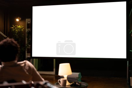 Photo for Man watching football competition live on ultrawide isolated screen smart TV, cheering for favorite team. Sports fan on couch in front of mockup television set display looking at soccer - Royalty Free Image