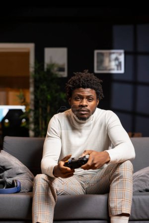 Photo for Portrait of man playing boring videogame on gaming console, feeling turned off by uninteresting levels. Gamer at home disappointed by game, struggling to maintain interest, using joystick controller - Royalty Free Image