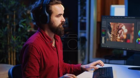 Photo for Close up on video editor putting headphones on in order to polish raw footage and improve audio quality. Videographer professionally adjusting clips, applying sound effects to film - Royalty Free Image