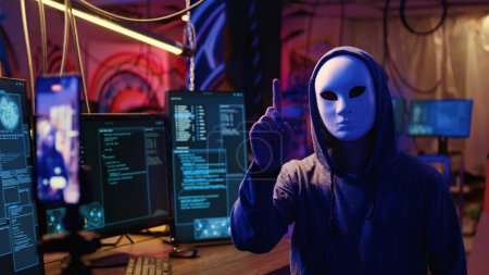 Maskierte Hacker filmen Video und drohen damit, die Koordinierung von DDoS-Angriffen auf Webseiten nicht einzustellen und große Datenmengen aus mehreren Quellen zu senden, um sie zu überwältigen, wenn ihre Forderungen nicht erfüllt werden