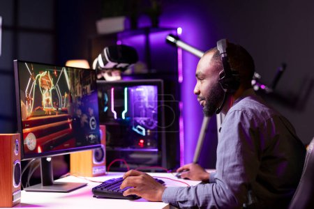 Man playing science fiction FPS videogame, having fun in dark apartment room, chatting with friends using headphones. Gamer competing in online esports game, shooting enemies with gun