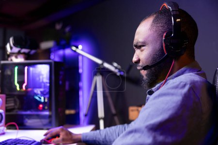 Photo for Man angry after losing while playing videogames in neon lit apartment. Irked gamer frustrated with defeat during multiplayer game, shot by other players, showing negative emotion - Royalty Free Image
