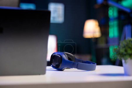 Photo for Selective focus on wireless headphones placed on a table near digital laptop. Image showing electronic devices kept on a desk for an individual to use. - Royalty Free Image