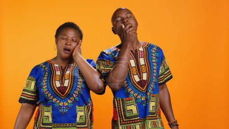 Photo for Exhausted husband and wife yawning on camera, dealing with burnout and feeling extremely tired. African american couple falling asleep standing over orange background, sleepy people. - Royalty Free Image