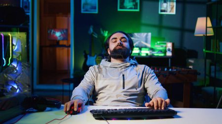 Homme paresseux binging jeux vidéo à la maison toute la journée, se sentant sans vie et déconnecté de la réalité, mentalement en difficulté. Joueur sédentaire faisant marathon de jeu dans l'appartement, se sentant léthargique et somnolent