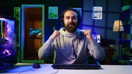 Esports player recording himself playing videogames in front of online viewers during livestream, providing engaging commentary while battling foes. Pro gamer streaming gaming session