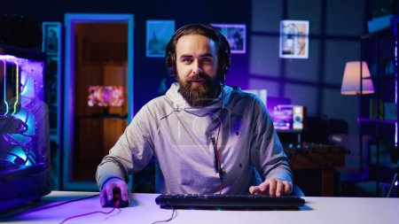 Excited esports player recording playing videogames in front of audience during livestream, providing engaging commentary while battling opponents. Pro gamer participating in gaming competition