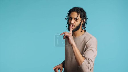 Middle Eastern man pretending to fight, throwing punches, holding defensive guard. BIPOC martial artist person mock boxing, holding combat stance, exercising in blue studio background, camera A