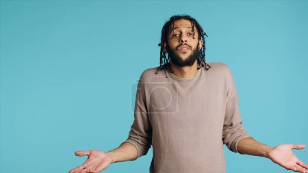 Photo for Uncaring Middle Eastern man shrugging shoulders, showing indifference and apathy. Careless BIPOC person doing nonchalant indifferent hand gesturing, isolated over studio background, camera A - Royalty Free Image