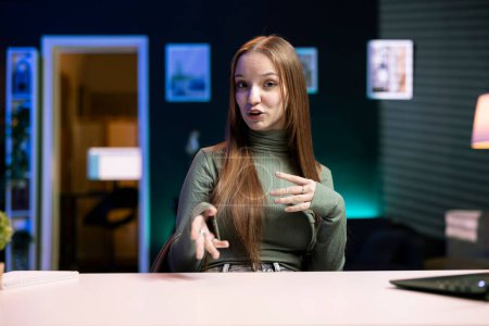 Porträt eines Teenagers, der Inhalte für einen Online-Streamingkanal im Studio filmt und damit die Fans unterhält. Gen z Influencer sitzt zu Hause am Schreibtisch und interagiert mit Abonnenten