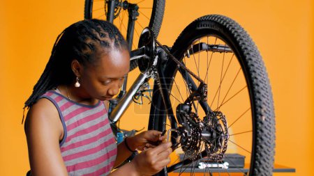Specialist using screwdriver and hex socket wrench to secure wheel on bicycle in studio background repair shop. Technician screwing bolts on bike parts, fixing rear derailleur, camera B
