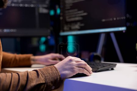 Freelancing cybersecurity admin using computer to look for company security vulnerabilities. IT engineer typing on keyboard, installing fortified code on PC to prevent cyber attacks, close up