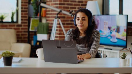 Photo for Prospecting job candidate remotely being interviewed via online videocall. Woman wearing headphones answering HR interview questions during videoconference meeting while staying at home, camera B - Royalty Free Image