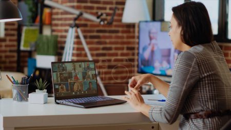 Photo for Teleworking team leader in cozy apartment discussing with coworkers during videoconference meeting. Company manager at home holding online videocall with workers, camera B - Royalty Free Image
