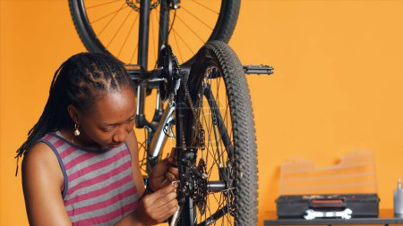 Specialist using screwdriver and hex socket wrench to secure wheel on bicycle in studio background repair shop. Technician screwing bolts on bike parts, fixing rear derailleur, camera A