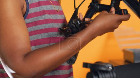 Photo for Handyman uses screwdriver to tighten brake levers screws on bicycle handlebars, studio background . Close up shot of repairman unscrewing damaged bike parts in order to refurbish them - Royalty Free Image