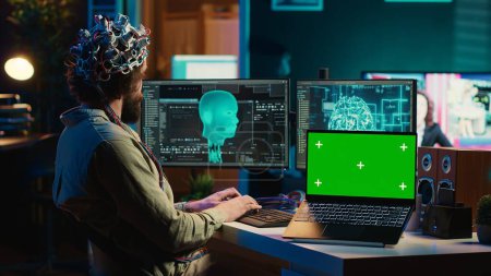 Computer scientist uploading brain into cyberspace, gaining digital persona using green screen laptop. Neuroscientist merging mind with AI, uploading consciousness into chroma key device, camera A