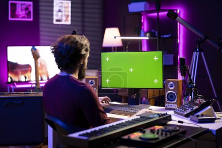 Ingeniero de sonido aprendiendo a mezclar y dominar grabaciones de audio viendo tutoriales de postproducción en línea en PC con pantalla verde. Artista edición de melodías y ajuste de niveles de volumen en el estudio en casa.