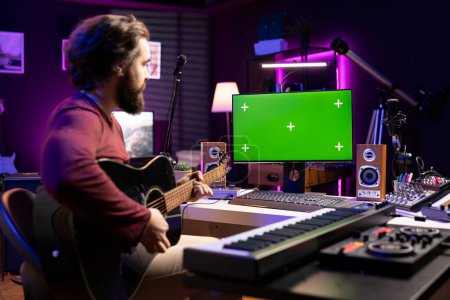 Künstler lernen das Gitarrespielen mit Internet-Unterricht auf Greenscreen-Monitor, sehen Tutorials für die Akustik-Probe im Heimstudio. Produzent lernt neue Saiten-Akkorde für Musikindustrie.