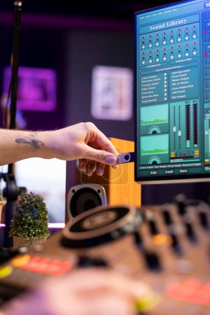 Talented producer using an usb stick to edit recorded audio files in home studio, working in post production. Young sound engineer adding audio effects mixing and mastering tunes, daw software.