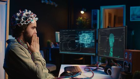 Téléchargez les photos : Technicien informatique utilisant casque EEG stupéfié après esprit processus virtuel de téléchargement est réussi. L'homme étonné après avoir atteint l'objectif de transférer la conscience dans le cyberespace informatique, caméra B - en image libre de droit