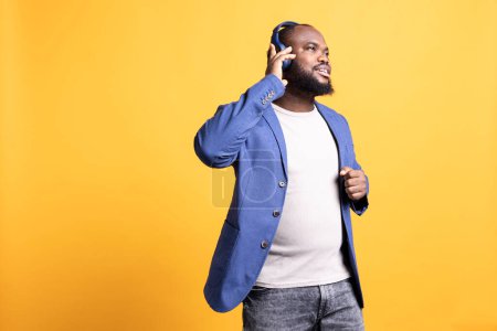 Foto de Hombre afroamericano divirtiéndose escuchando música en auriculares, bailando, disfrutando de canciones en la radio. Persona BIPOC sentirse relajado y despreocupado, melodías auditivas, fondo de estudio - Imagen libre de derechos